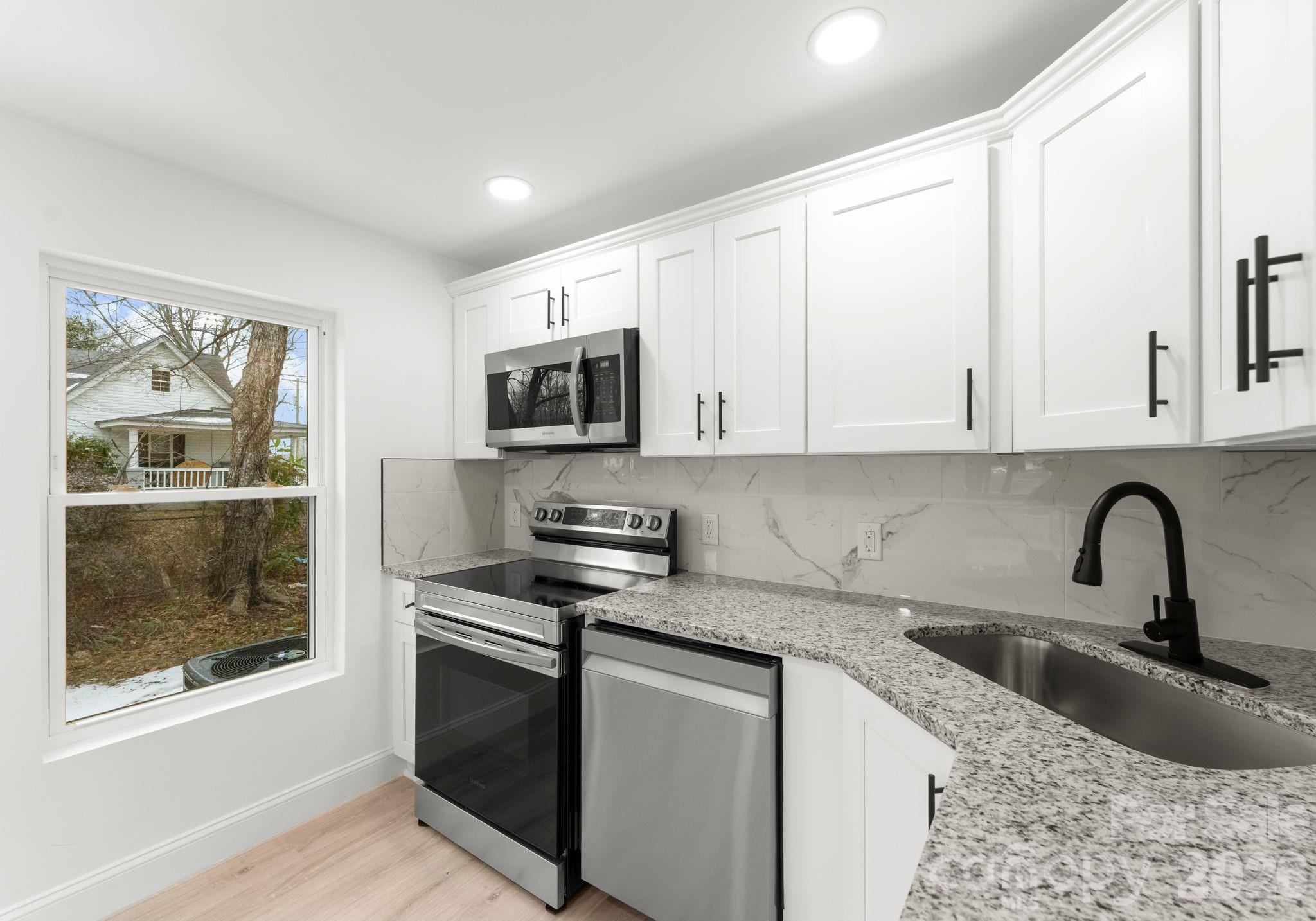 1413 Modena Street Gastonia, NC 28054 - Photo 25 of 27 a kitchen with stainless steel appliances granite countertop a stove a sink and a microwave