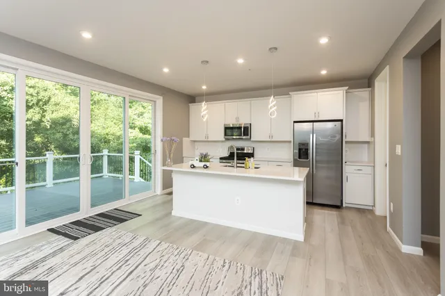 a kitchen with stainless steel appliances granite countertop a refrigerator a sink dishwasher a stove and white countertops with wooden floor