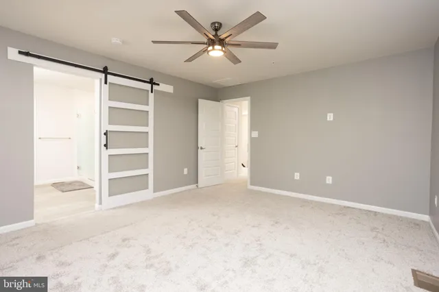 an empty room with windows and ceiling fan