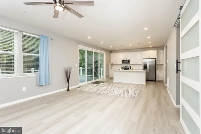 a large white kitchen with kitchen island a large window a sink and stainless steel appliances