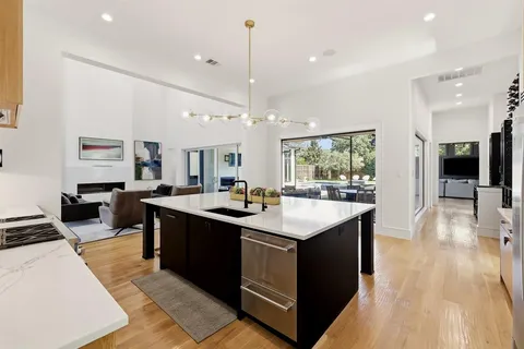 a kitchen with counter top space sink stove and wooden floor