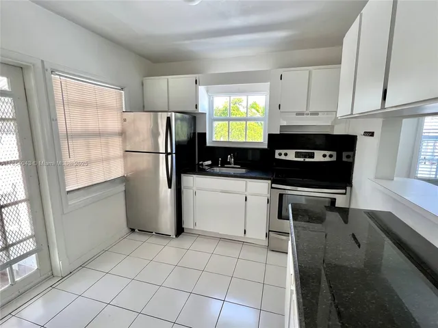 a kitchen with a refrigerator a stove a sink a counter top space and cabinets