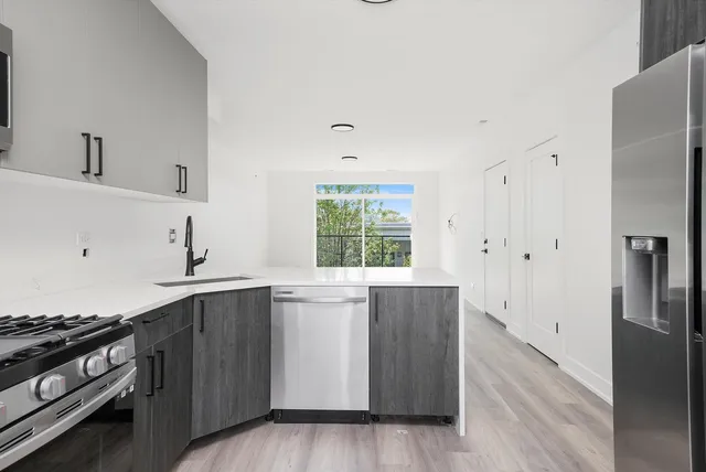 a kitchen with stainless steel appliances a stove a sink and wooden cabinets