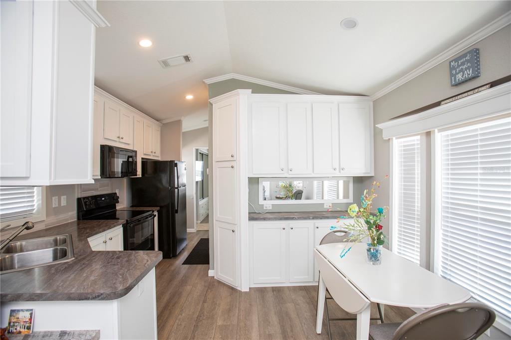 5642 Oak Ridge Avenue New Port Richey, FL 34652 - Photo 8 of 44 a kitchen with a refrigerator a stove a sink dishwasher with a dining table and chairs