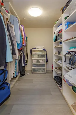 a view of walk in closet with clothes and shoes