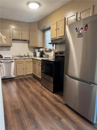 a kitchen with granite countertop a refrigerator stove top oven and cabinets