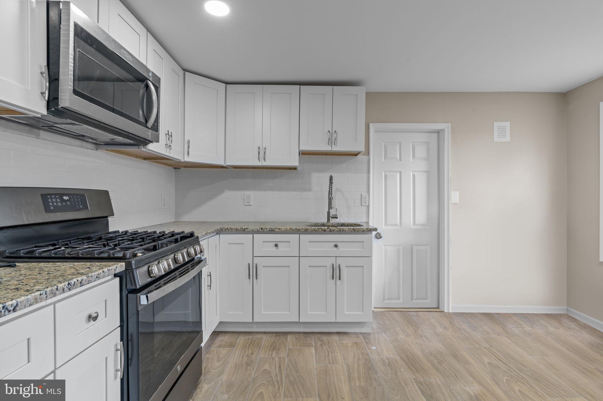 327 Mercer Street Gloucester City, NJ 08030 - Photo 4 of 19 a kitchen with stainless steel appliances granite countertop a stove a microwave and cabinets