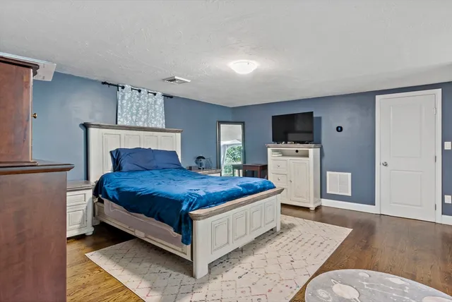 a spacious bedroom with a bed and a flat screen tv