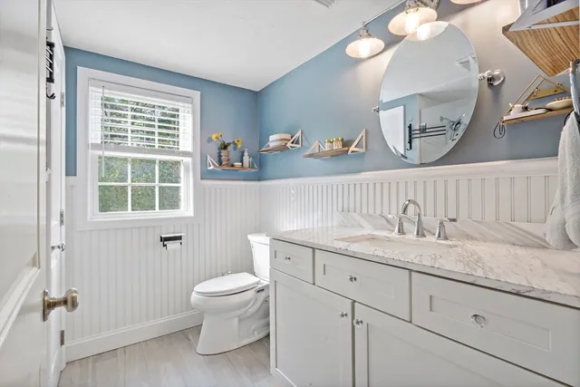 a bathroom with a granite countertop sink a toilet and a window