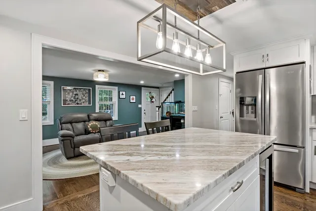 a kitchen with stainless steel appliances granite countertop a refrigerator a sink dishwasher a stove and white cabinets