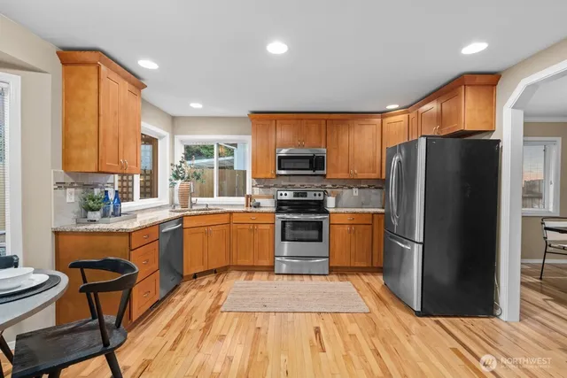 a kitchen with a refrigerator a stove top oven a sink dishwasher and wooden cabinets with wooden floor