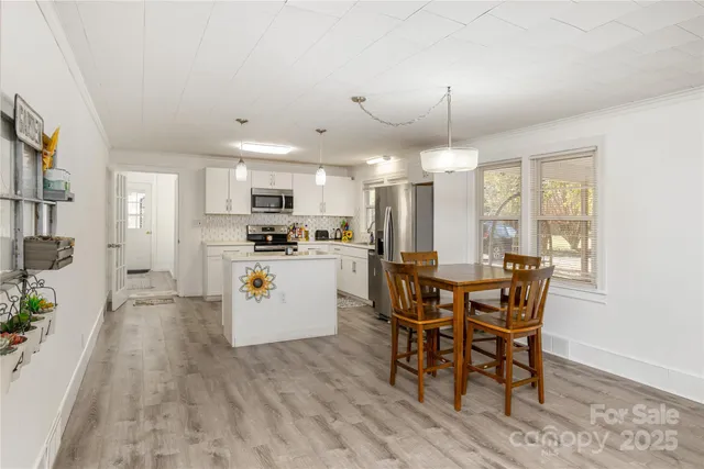 a kitchen with a table chairs a sink dishwasher window and cabinets