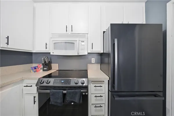 a kitchen with stainless steel appliances granite countertop a refrigerator stove and white cabinets