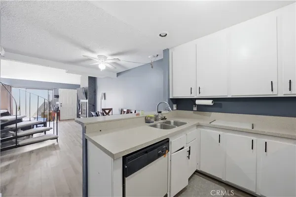 a view of a kitchen counter space a sink dishwasher and a stove with wooden floor