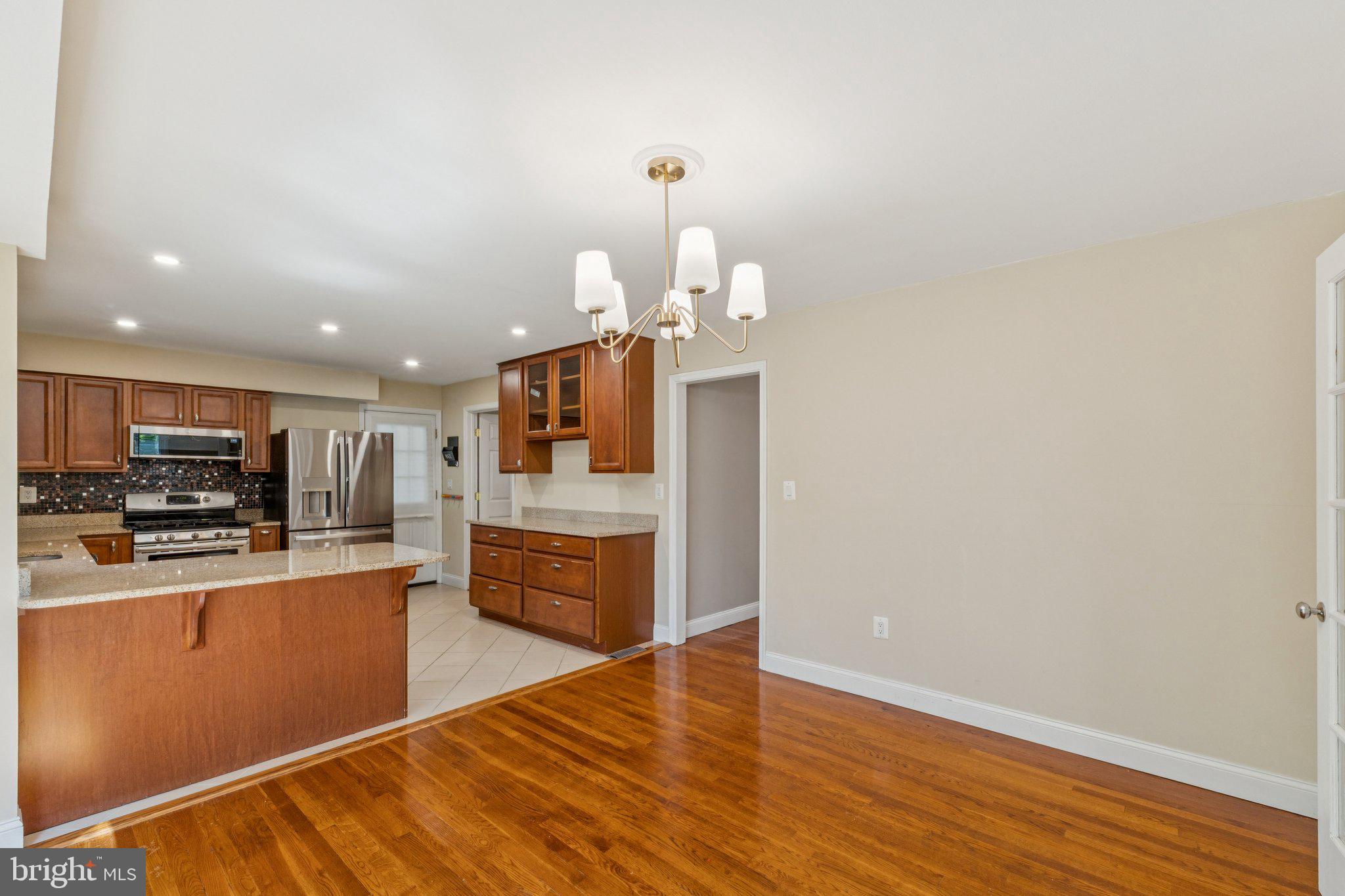 1900 Briggs Road Silver Spring, MD 20906 - Photo 9 of 44 a kitchen with stainless steel appliances granite countertop a refrigerator a stove top oven a sink dishwasher and wooden floor