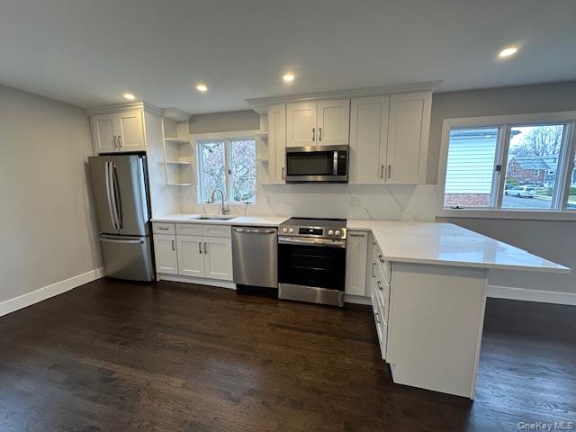 5 Linwood Road North, Unit 2 Port Washington, NY 11050 - Photo 2 of 12 Kitchen featuring a peninsula, stainless steel appliances, open shelves, white cabinetry, and dark wood-style floors