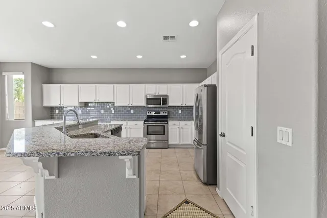 a kitchen with stainless steel appliances granite countertop a refrigerator sink and stove