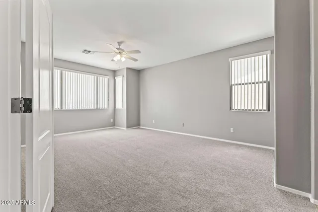an empty room with windows and ceiling fan
