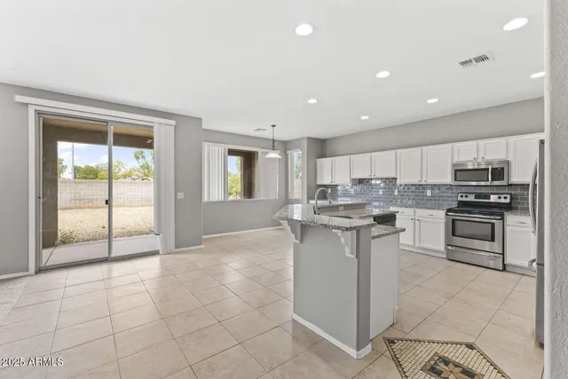 a kitchen with stainless steel appliances granite countertop a stove top oven a sink and a refrigerator
