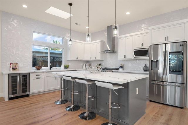 a kitchen with a sink a center island stainless steel appliances and cabinets