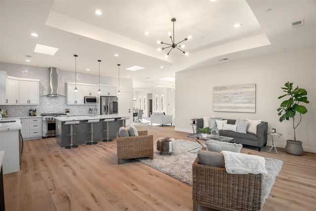 a large living room with stainless steel appliances kitchen island granite countertop furniture a rug kitchen view and a chandelier