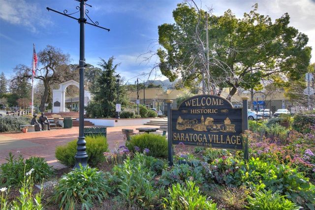 a sign board with a house and garden in the background