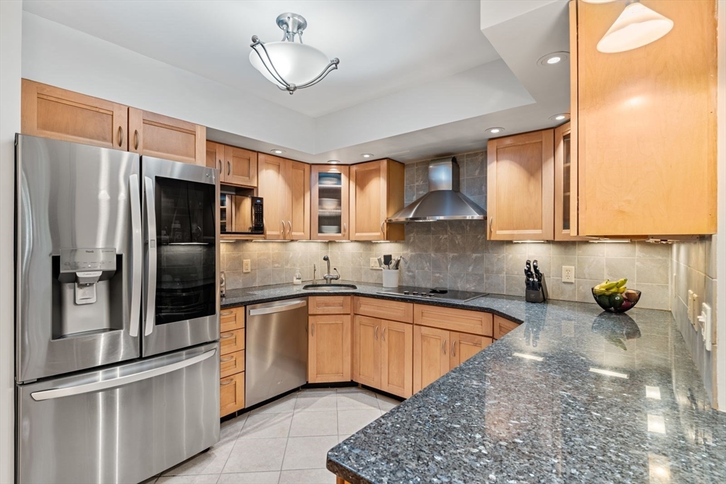 a kitchen with stainless steel appliances granite countertop a sink refrigerator and cabinets