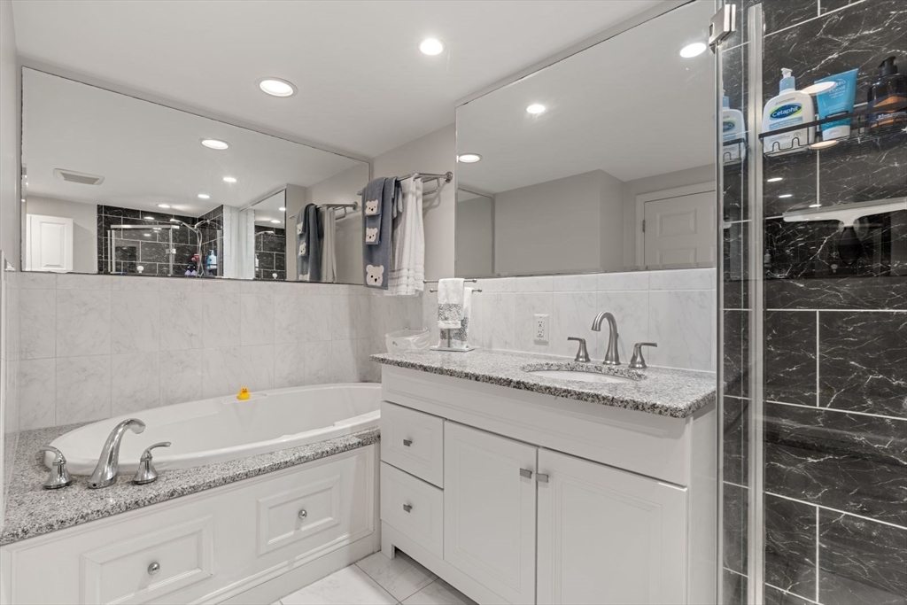 135 Franklin Street, Unit 101 Stoneham, MA 02180 - Photo 15 of 24 a bathroom with a granite countertop double vanity sink and mirror