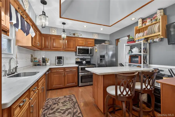 a kitchen with stainless steel appliances granite countertop a stove top oven a sink a dining table and chairs with wooden floor