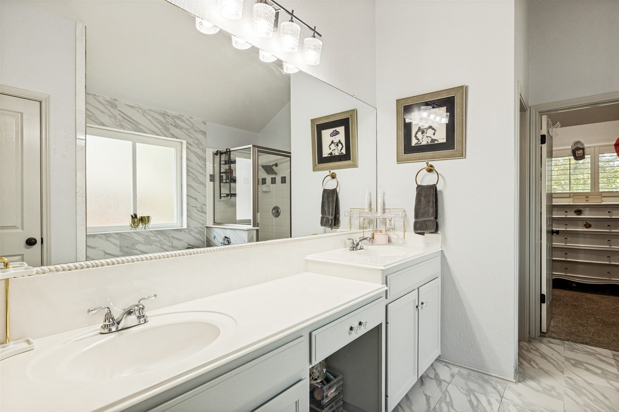 3803 Caney Creek Road Austin, TX 78732 - Photo 14 of 21 A spacious double vanity features clean white countertops alongside elegant marble-patterned tile flooring.