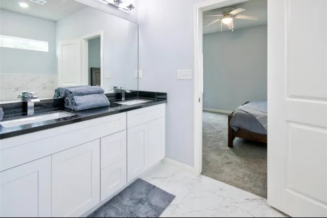a en suite bathroom with a granite countertop sink and a mirror