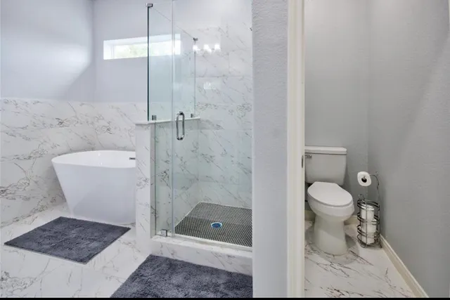 a bathroom with a granite countertop toilet a sink a shower and mirror