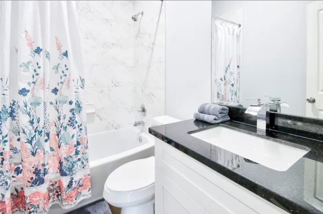 a bathroom with a granite countertop sink a toilet and a bathtub