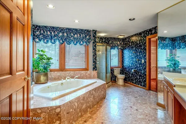 a spacious bathroom with a tub a double vanity sink a mirror and a shower