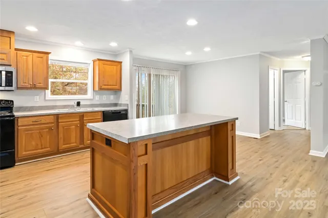a kitchen with a stove a sink a refrigerator and wooden floor