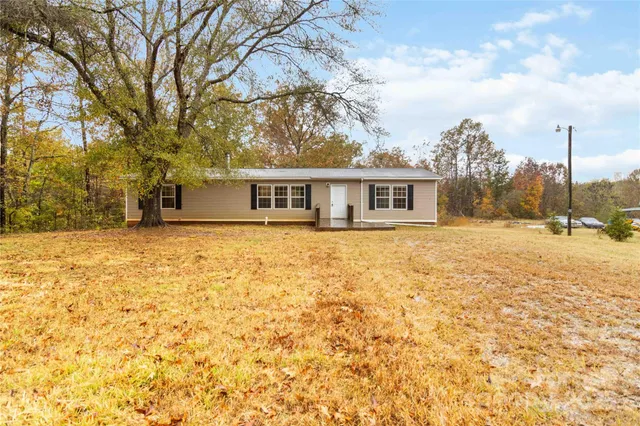 a view of house with yard and trees in the background