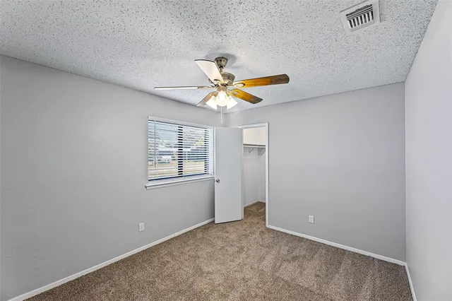 an empty room with a window and a fan