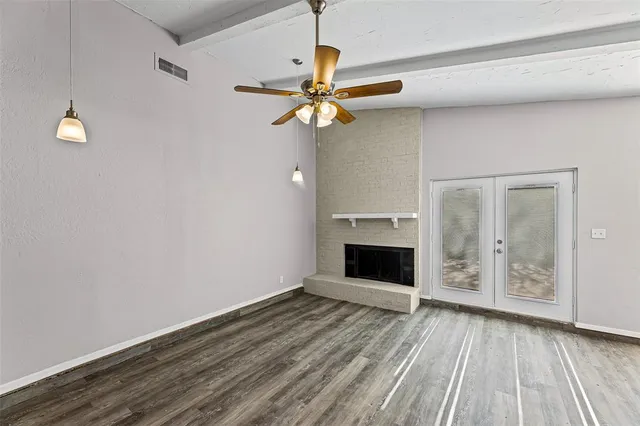 an empty room with wooden floor cabinet and windows
