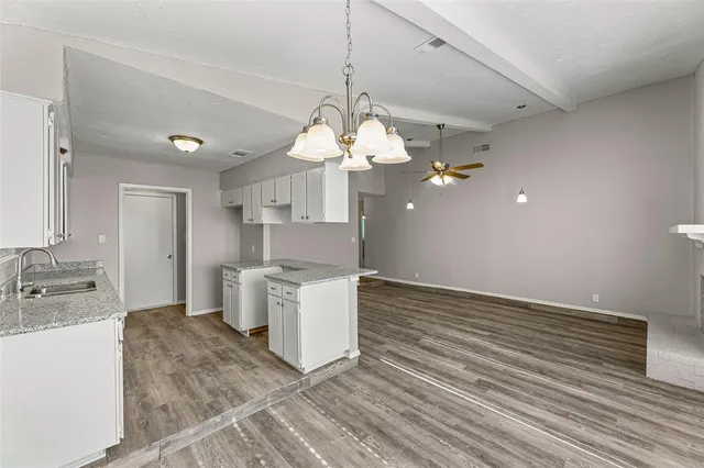 a kitchen with granite countertop a sink a counter space and cabinets