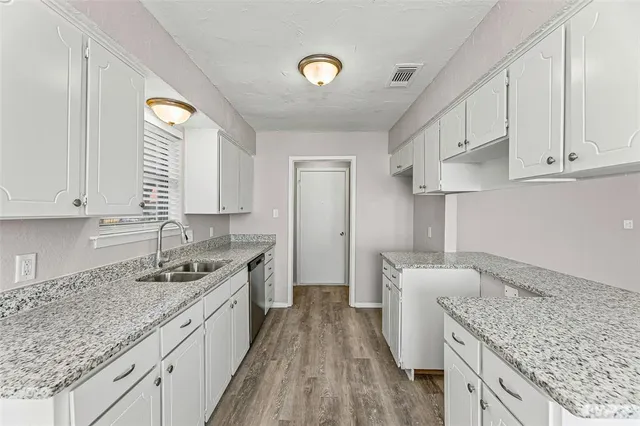 a kitchen with stainless steel appliances granite countertop a sink dishwasher and stove with wooden floor