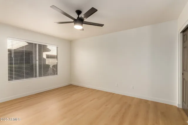 an empty room with a window and a fan