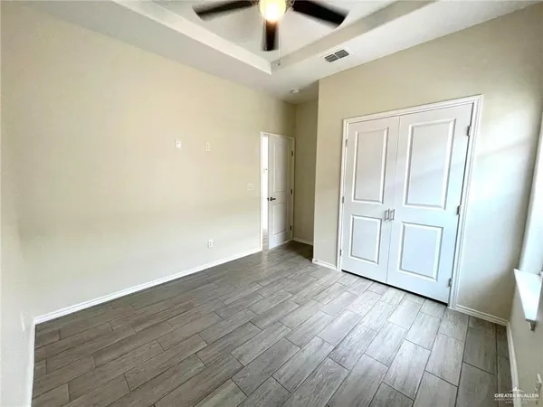 an empty room with wooden floor chandelier fan and windows