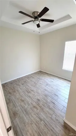 an empty room with wooden floor ceiling fan and window