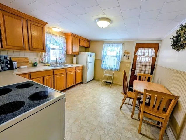 a kitchen with a refrigerator a stove top oven a sink a dining table and chairs