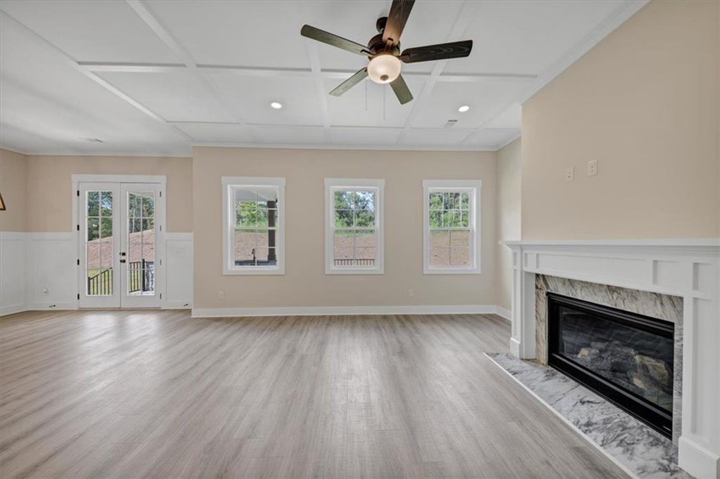 960 Oxford Road Ball Ground, GA 30107 - Photo 12 of 54 an empty room with wooden floor a fireplace a ceiling fan a fireplace and windows