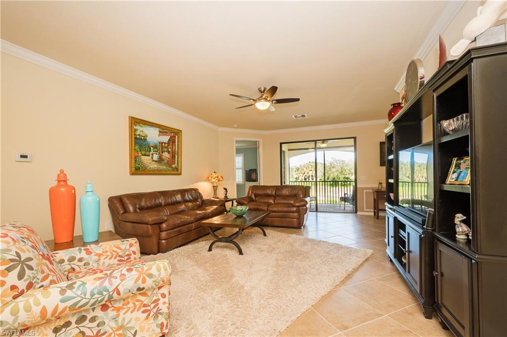 9511 Napoli Lane, Unit 202 Naples, FL 34113 - Photo 3 of 24 a living room with furniture a flat screen tv and a refrigerator