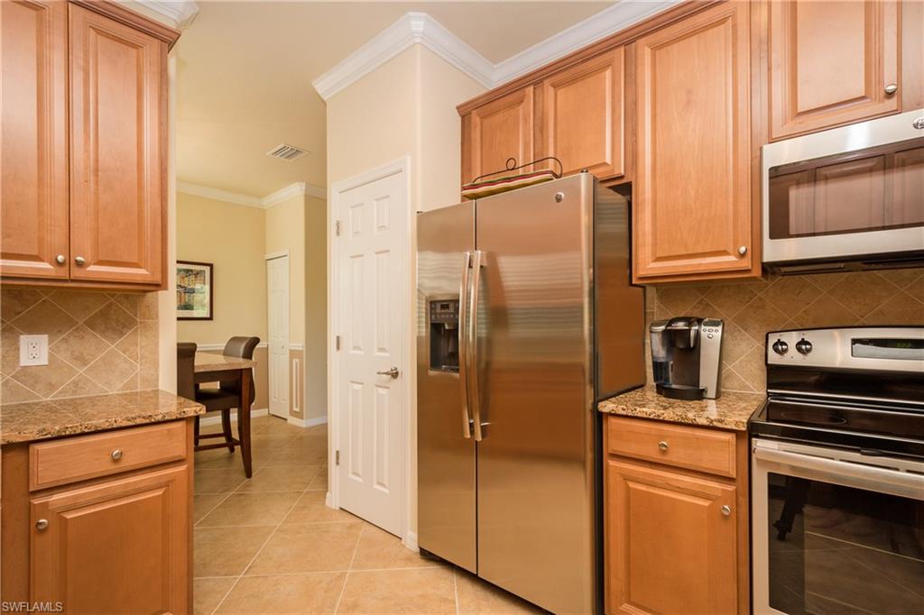 9511 Napoli Lane, Unit 202 Naples, FL 34113 - Photo 7 of 24 a kitchen with stainless steel appliances granite countertop a refrigerator and a stove top oven