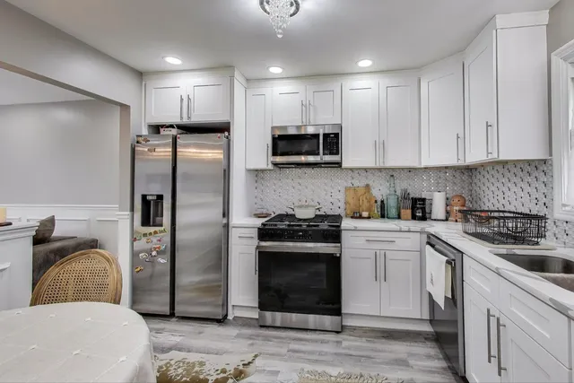 a kitchen with stainless steel appliances granite countertop a refrigerator a stove a sink and a microwave