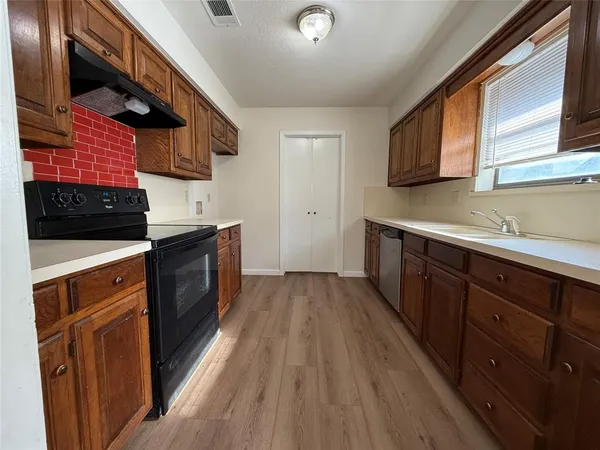 a kitchen with stainless steel appliances granite countertop wooden cabinets a stove top oven a sink and dishwasher