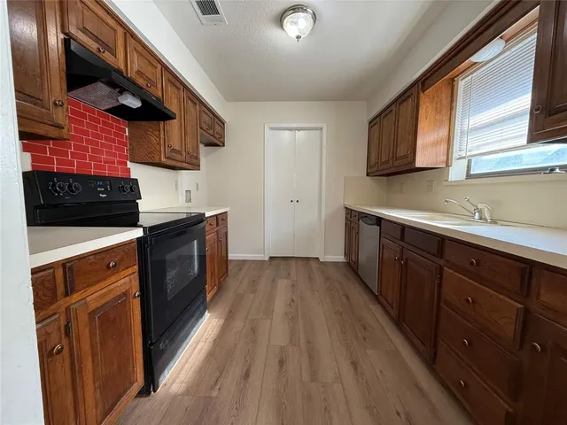 a kitchen with stainless steel appliances granite countertop wooden cabinets a stove top oven a sink and dishwasher